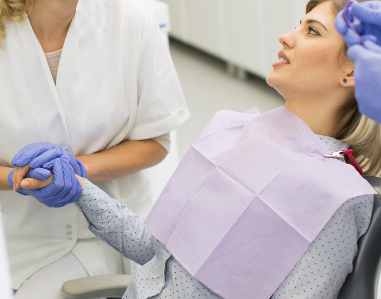 Dentist in blue gloves examining patient's arm in clinical dental office setting.