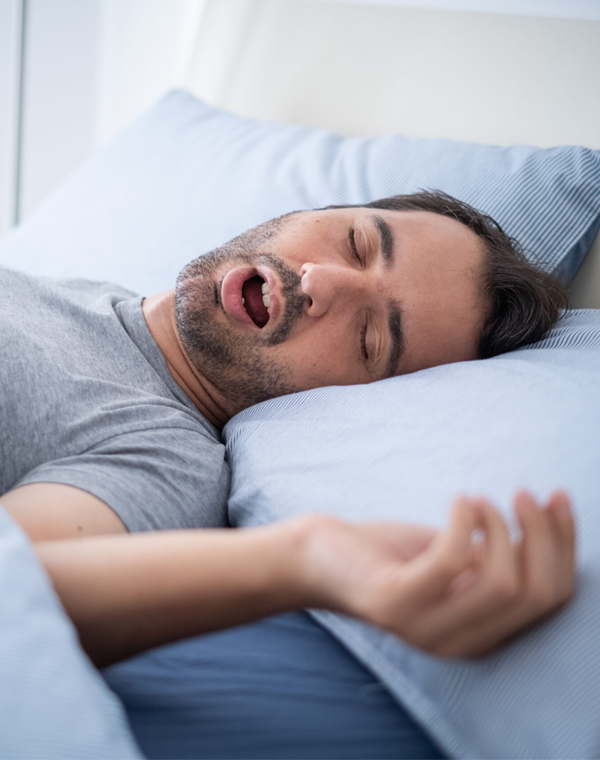 Man sleeping in bed, appearing to experience sleep disturbance or discomfort.